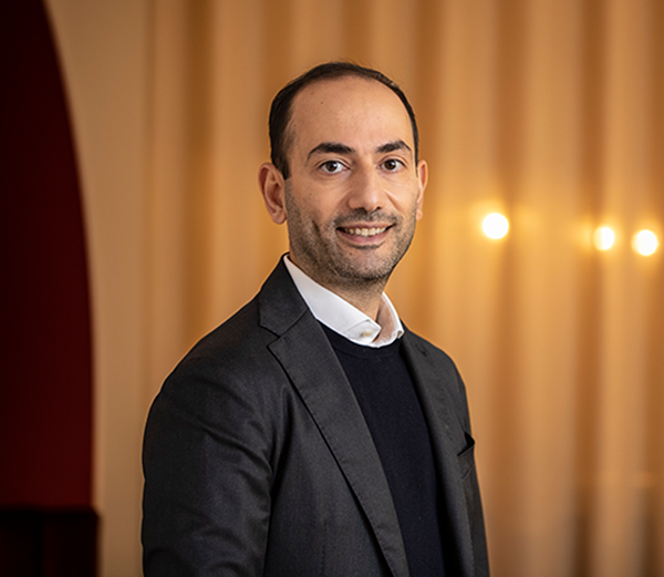 Leende man i kavaj står framför en varmtonad bakgrund