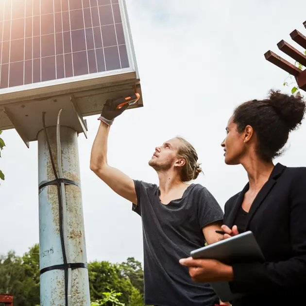 Två unga människor mäter på solpaneler.