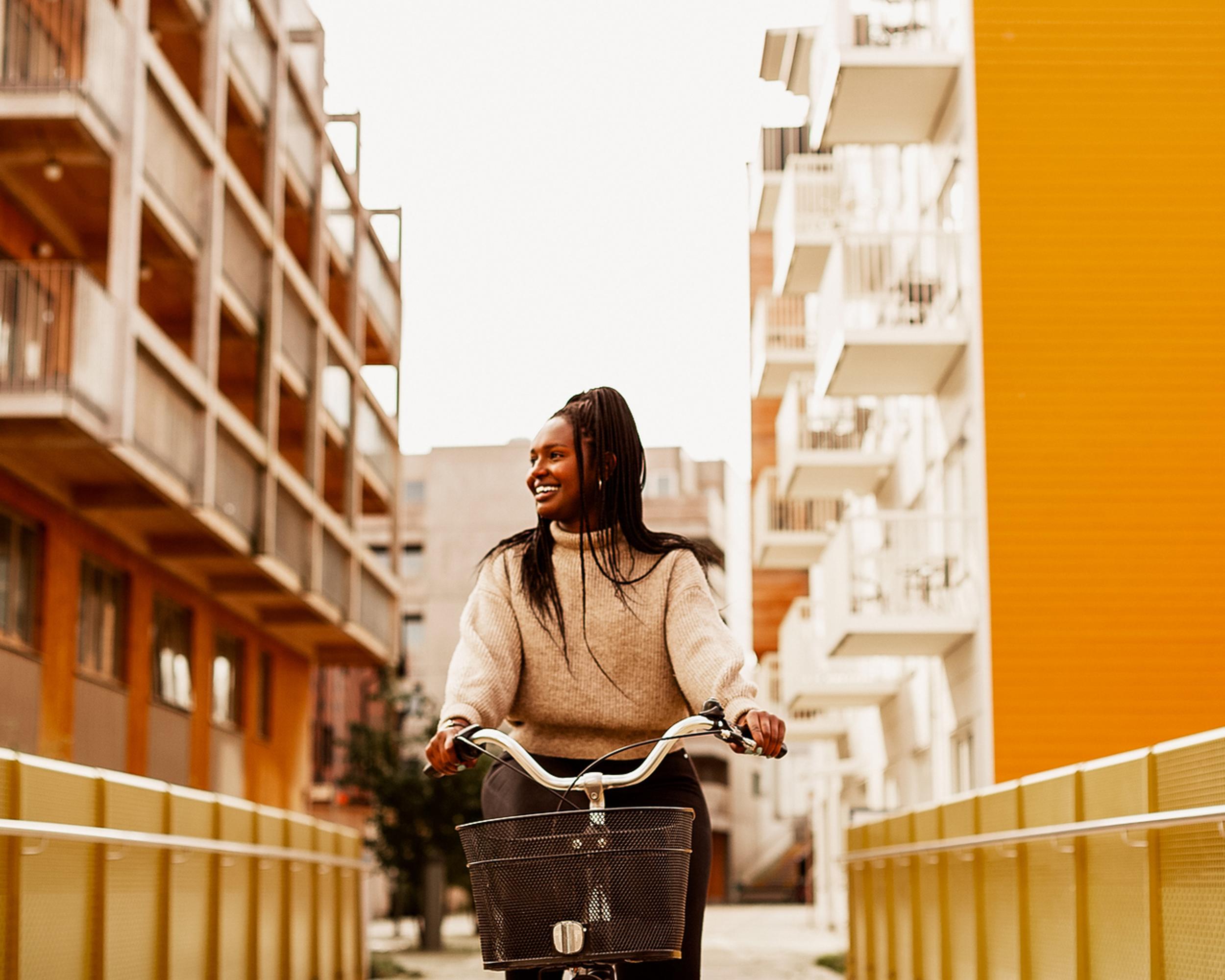 Glad kvinna cyklar mellan orange hus.