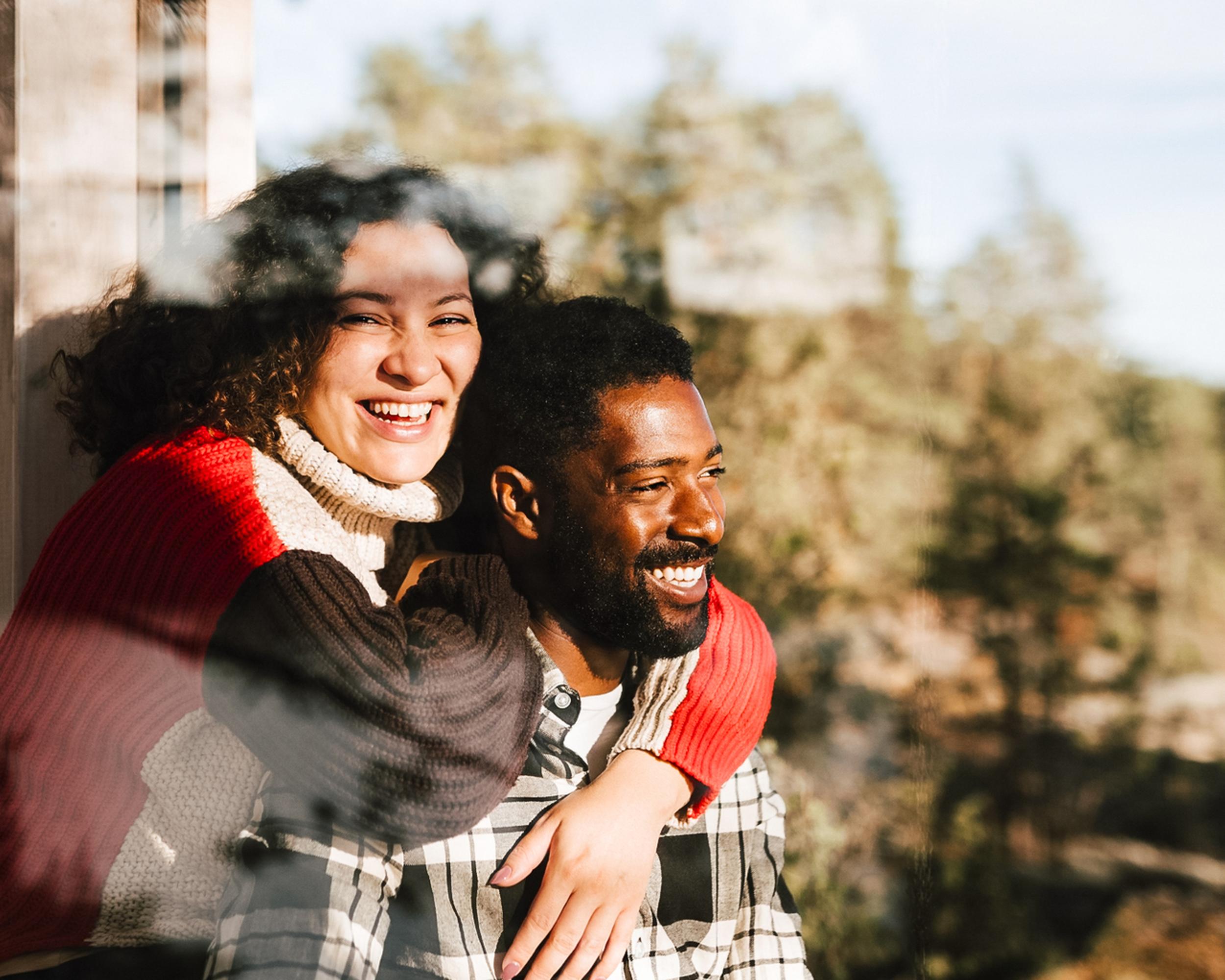 Ett glatt par vid ett fönster i en stuga i skogen.