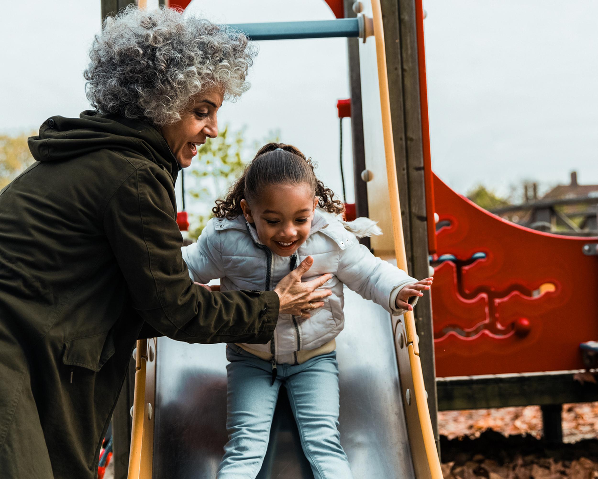 Pensionär med barnbarn i lekpark