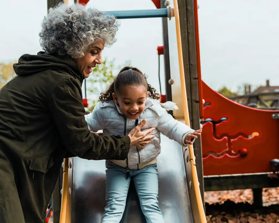 Pensionär med barnbarn i lekpark