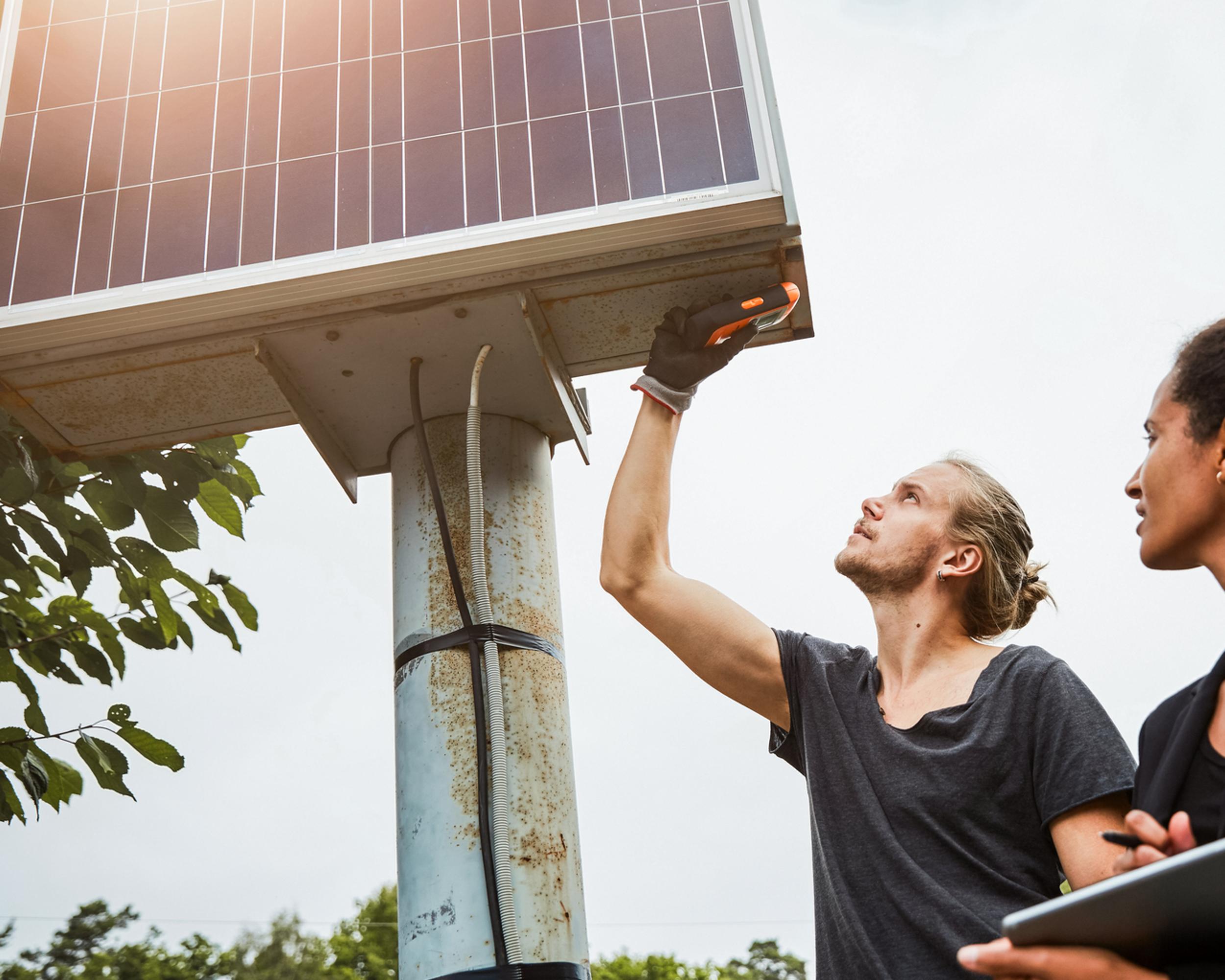 Två unga människor mäter på solpaneler.
