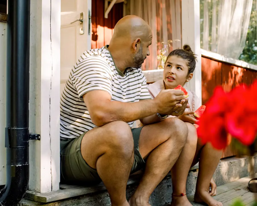 En vuxen och ett barn sitter på en trappa under sommaren.