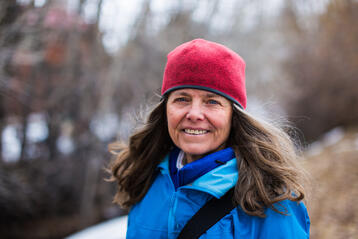 Kvinna i röd mössa och blå jacka står utomhus på vintern