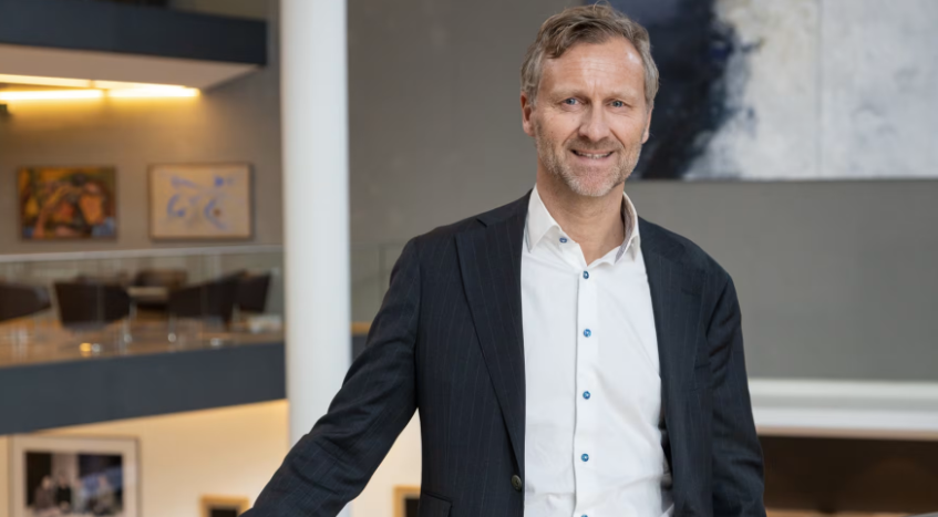 En man i kostym står i en modern kontorsmiljö med konstverk i bakgrunden