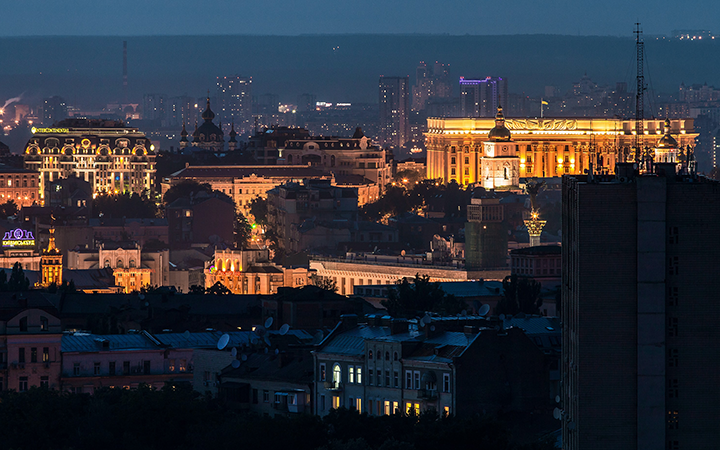 Stadsvy över Kiev på kvällen med upplysta byggnader och dimmigt stadslandskap