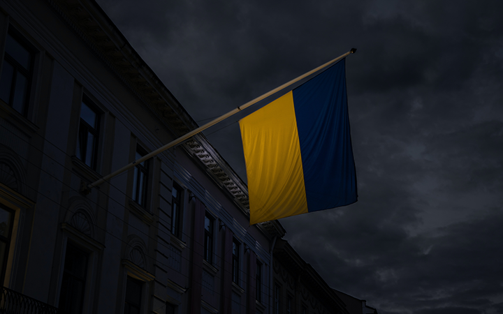 Ukrainas flagga vajar från byggnad i mörk stadsmiljö