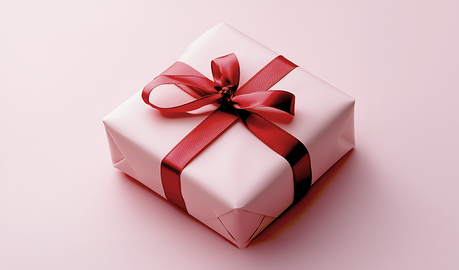 Rosa present förpackad med ett rött sidenband på en ljusrosa bakgrund