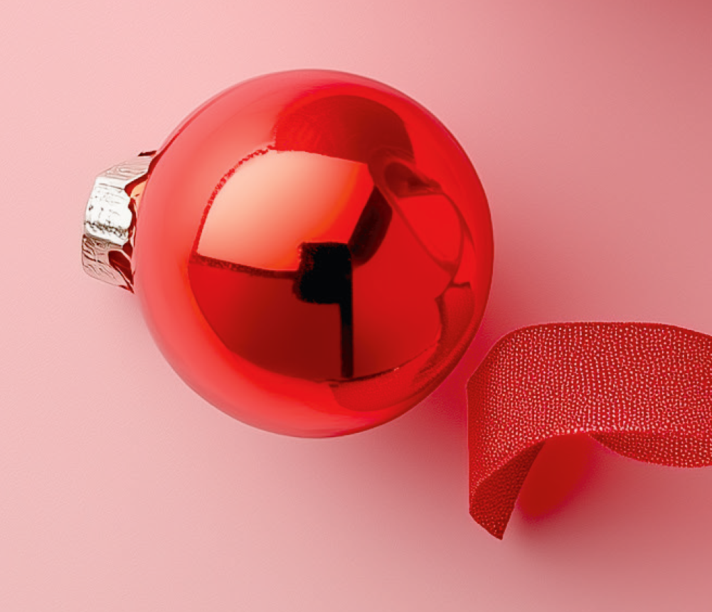 Röd julgranskula och band mot rosa bakgrund