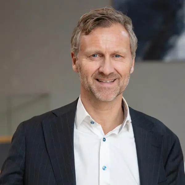 Man i kostym, ler mot kameran i en professionell miljö