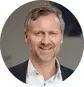 Man i kostym som ler framför en neutral bakgrund